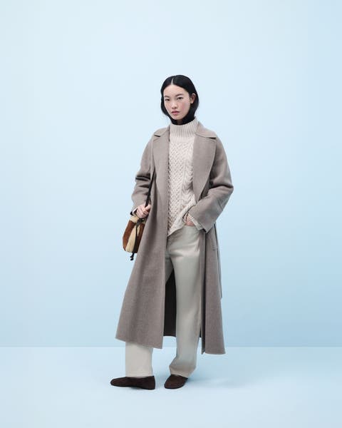 Woman wearing a turtleneck sweater, coat, pants, flats and a handbag.