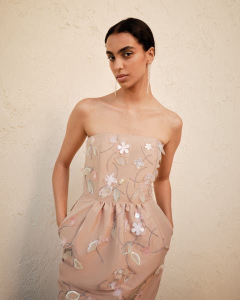 Woman wearing an embroidered Bernadette gown.
