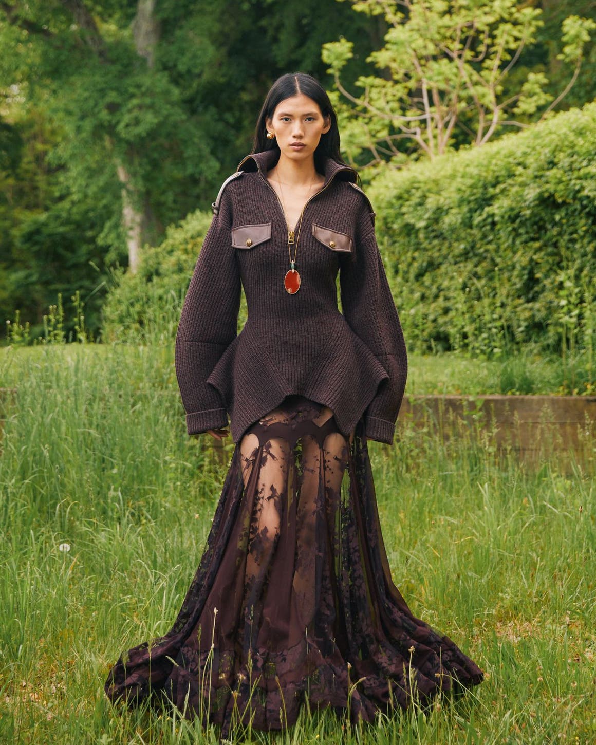 Woman wearing dark brown jacket with flowy gown.