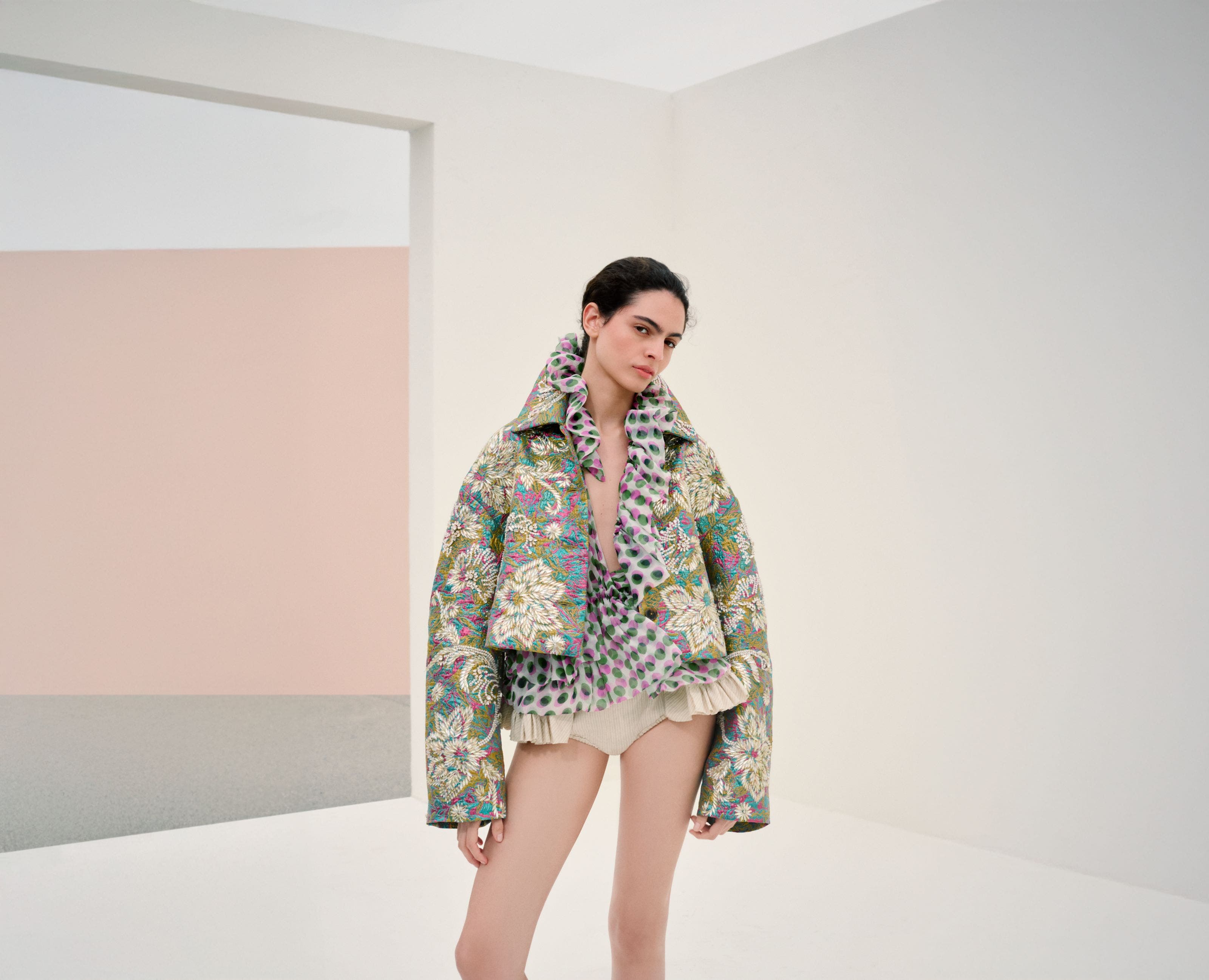 Woman wearing Dries Van Noten jacket, blouse and hot pants.