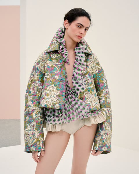 Woman wearing Dries Van Noten jacket, blouse and hot pants.