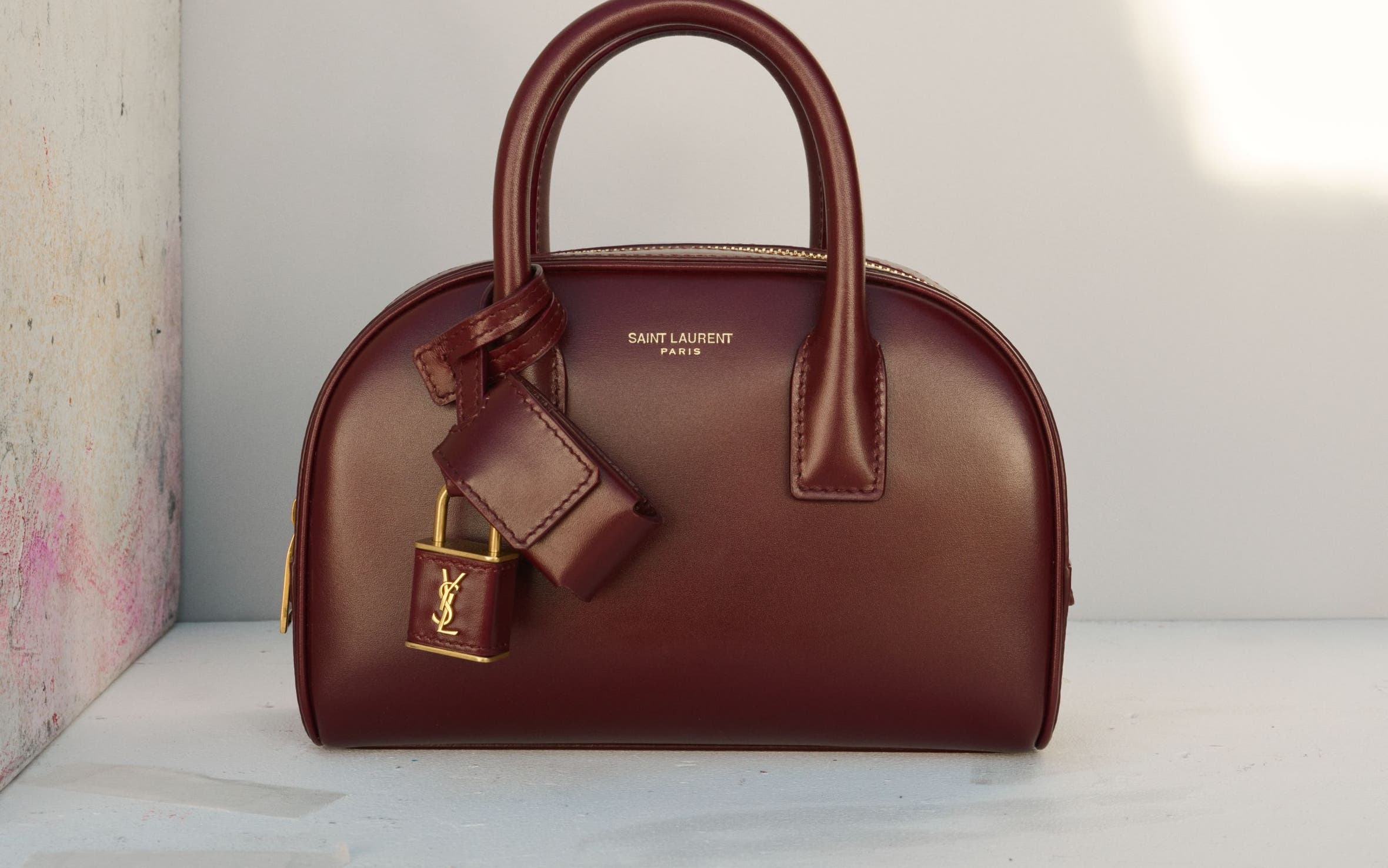 Structured top-handle handbag in burgundy leather with gold hardware.