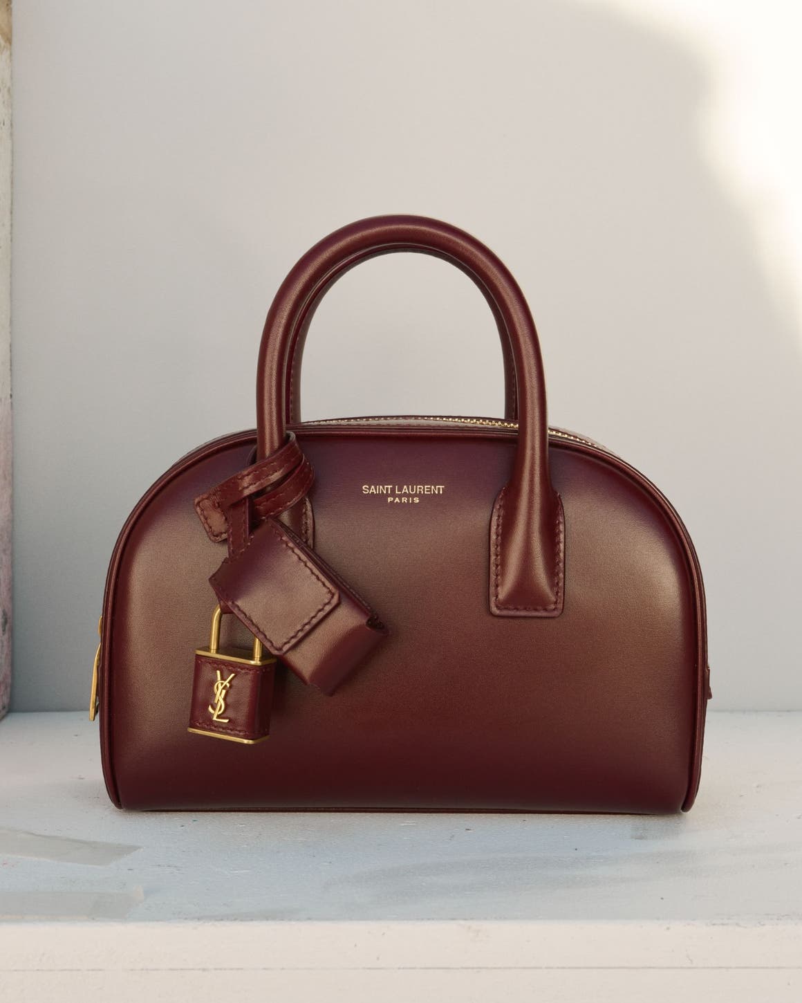 Structured top-handle handbag in burgundy leather with gold hardware.