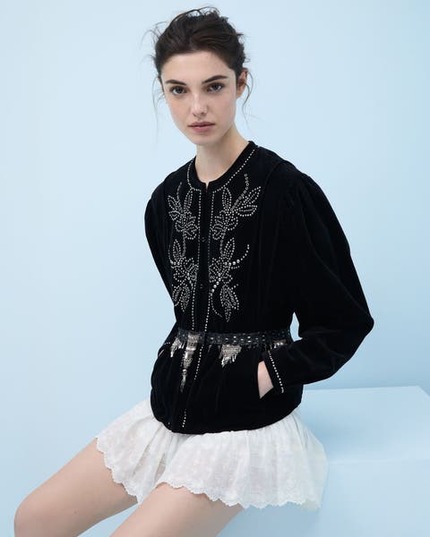 Woman wearing an embroidered sweater and mini skirt.