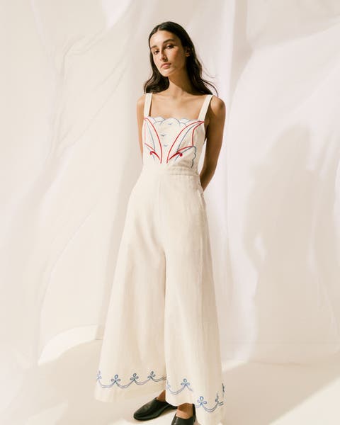 Woman wearing a white cardigan, long layered skirt and sandals.