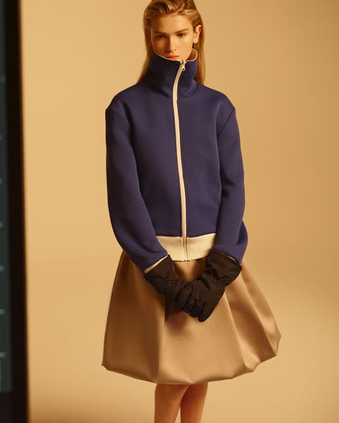woman in zip-up hoodie with beige bubble skirt.