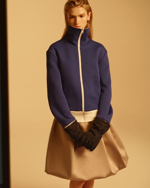 Split image showing a contact sheet of a woman in a blue turtleneck on the left, and a full styled shot on the right of a woman wearing a purple zip-front jacket, tan skirt and black gloves
