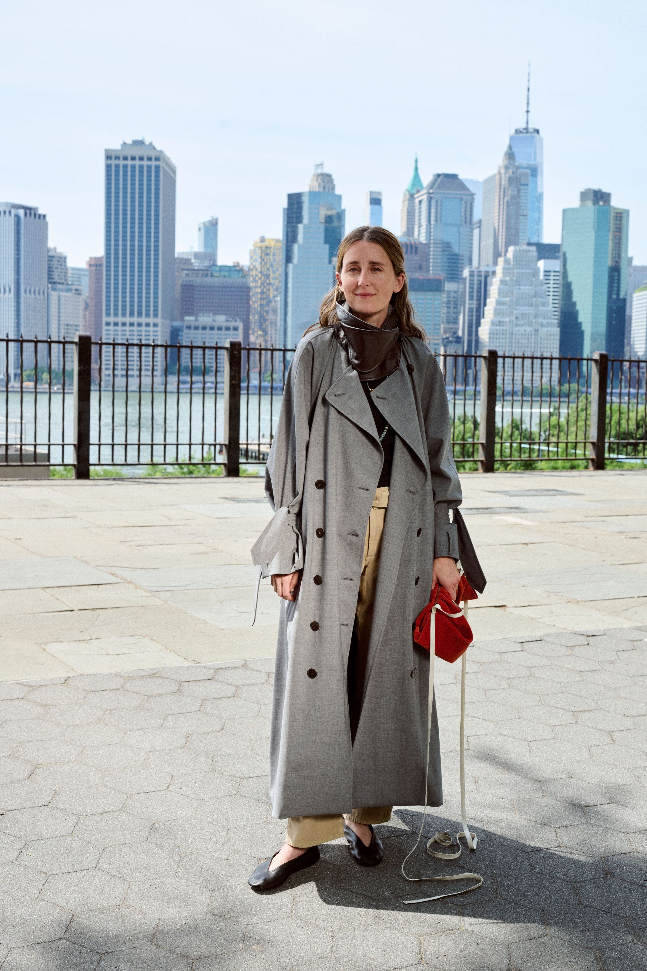 Woman in a long grey coat standing on a city street