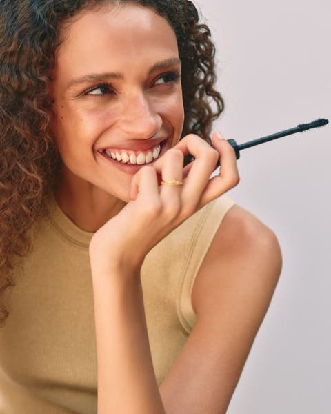 A woman applying mascara.