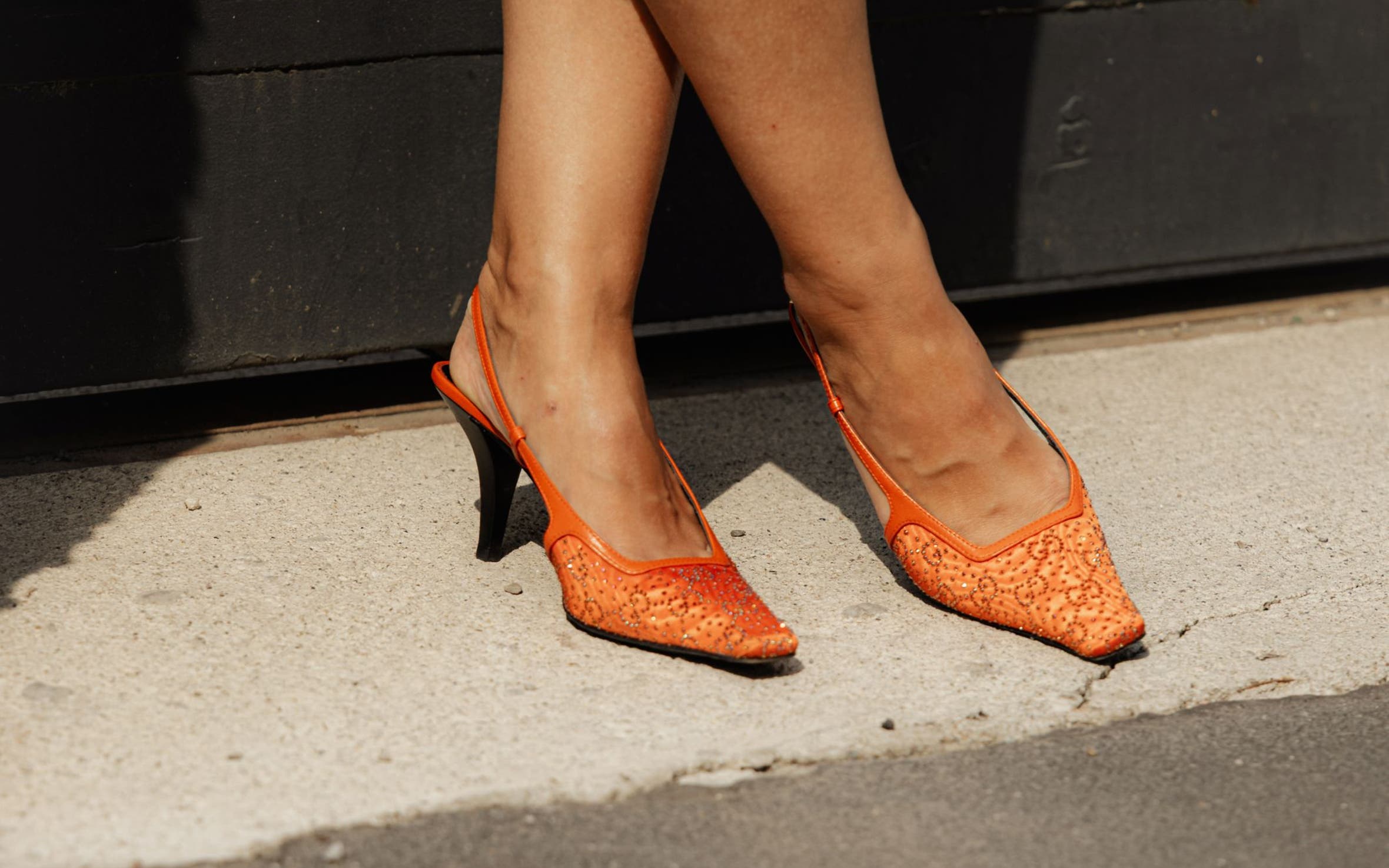 Woman wearing orange slingback sandals.
