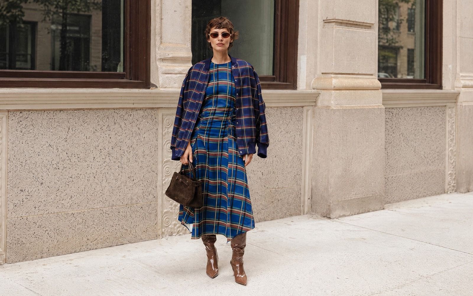 Model in navy plaid bomber jacket and matching plaid dress, street style