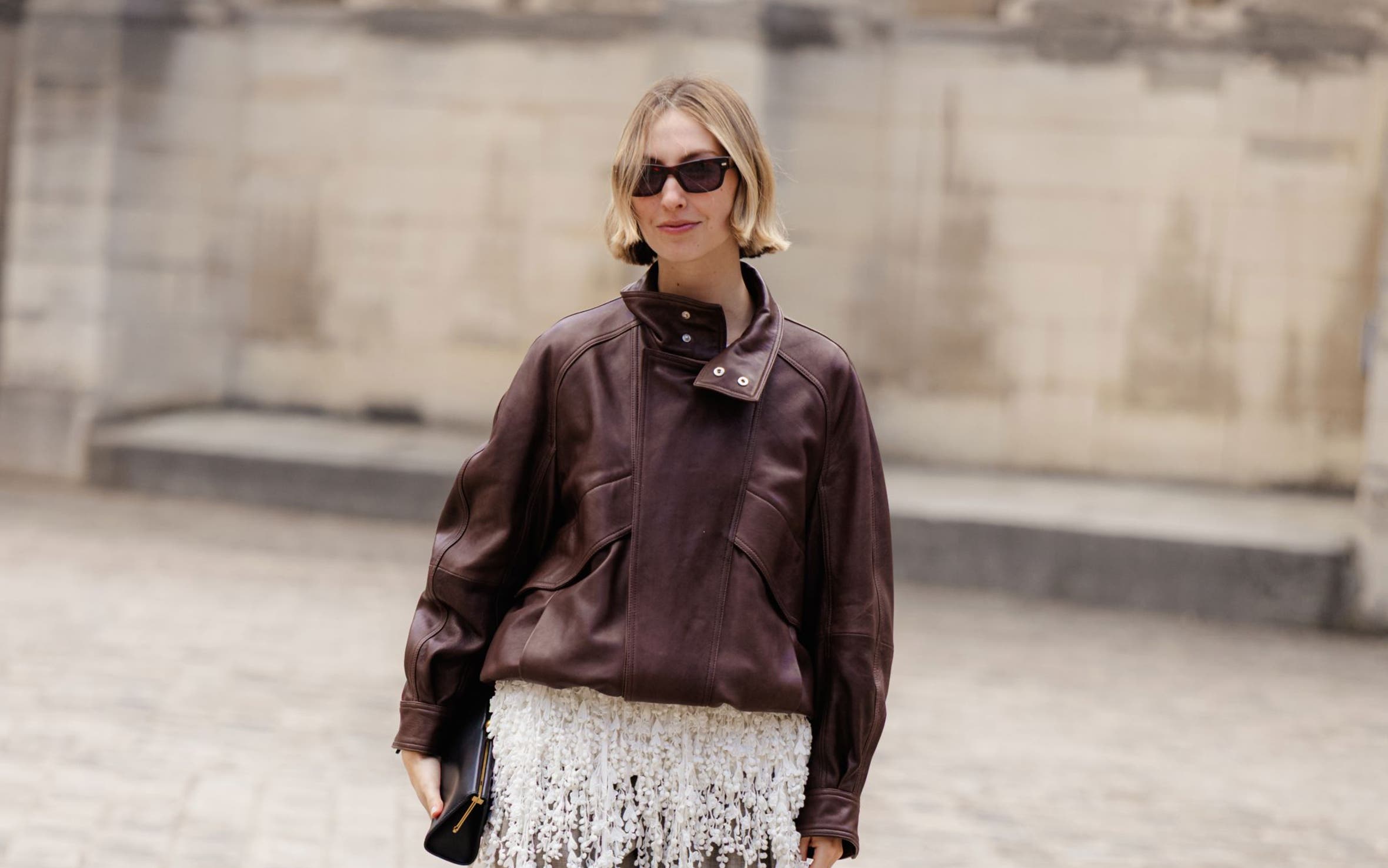 A woman wearing a leather jacket and wide-leg trousers. 