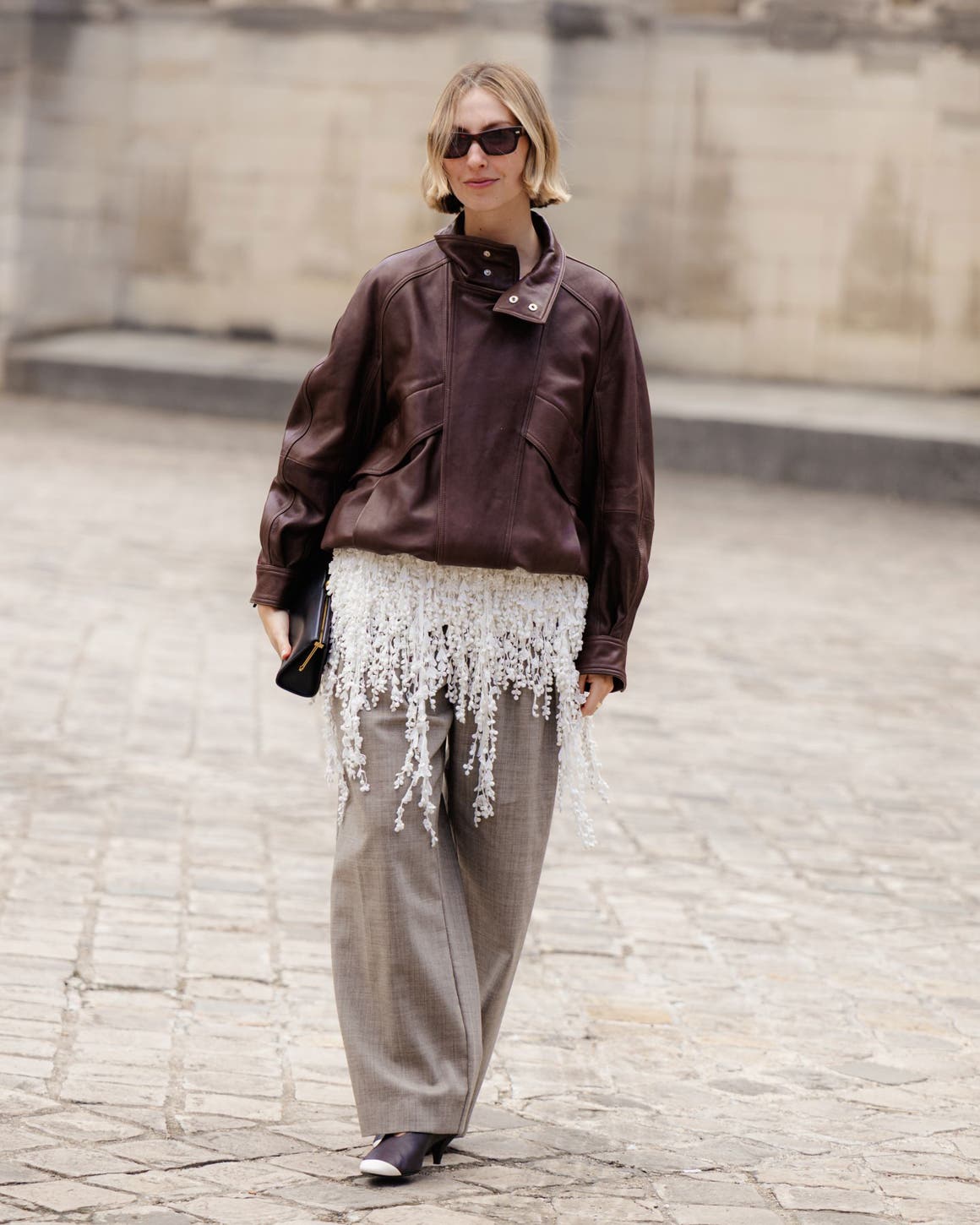 A woman wearing a leather jacket and wide-leg trousers. 