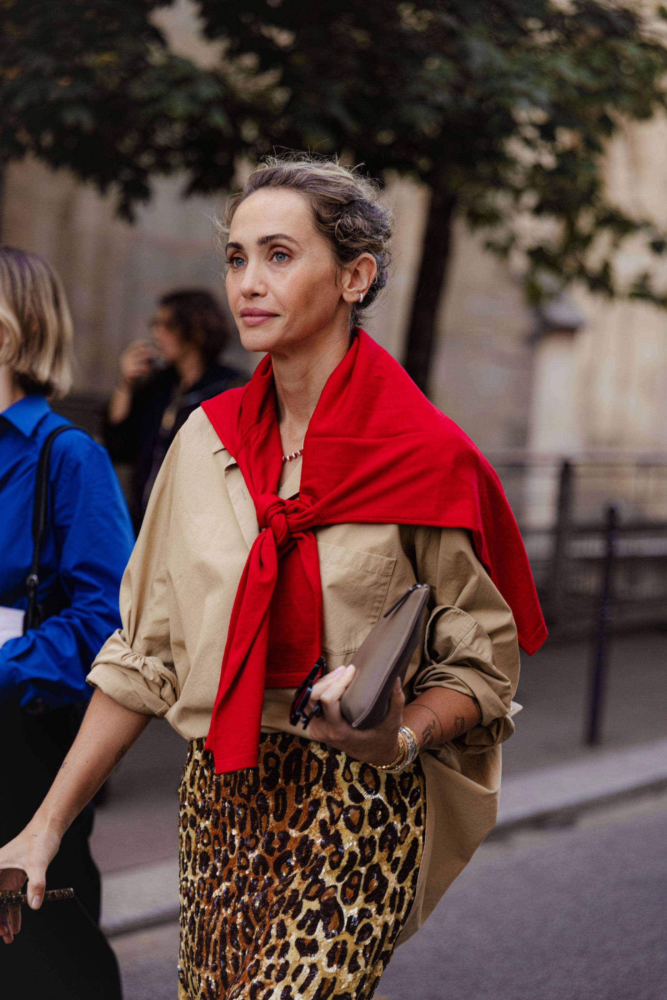 Woman in button-up, leopard skirt and red top tied around her shoulders.