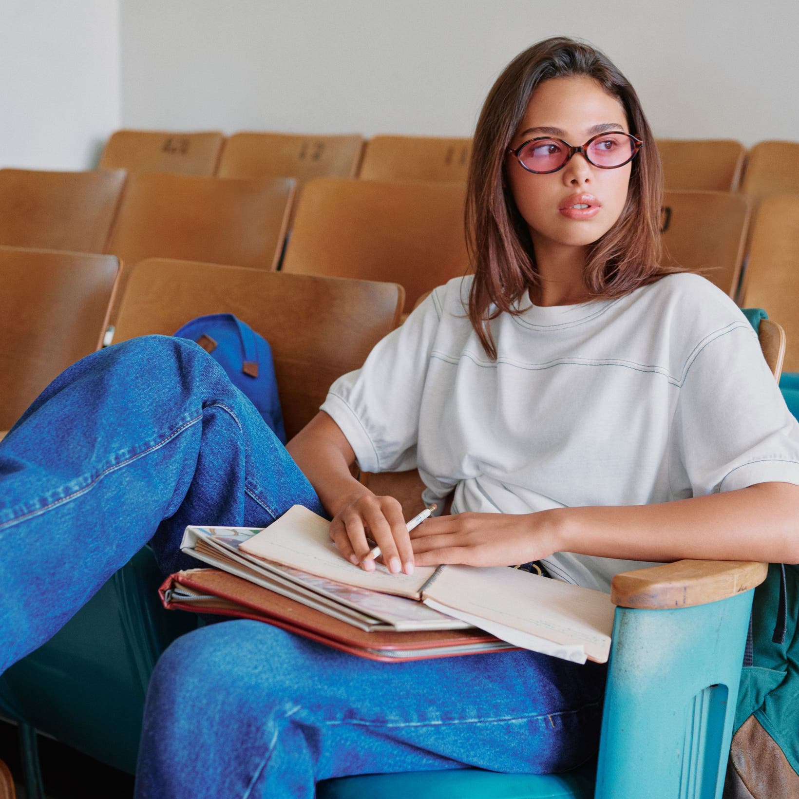 A student in a classroom wearing a Good American tee and jeans. 
