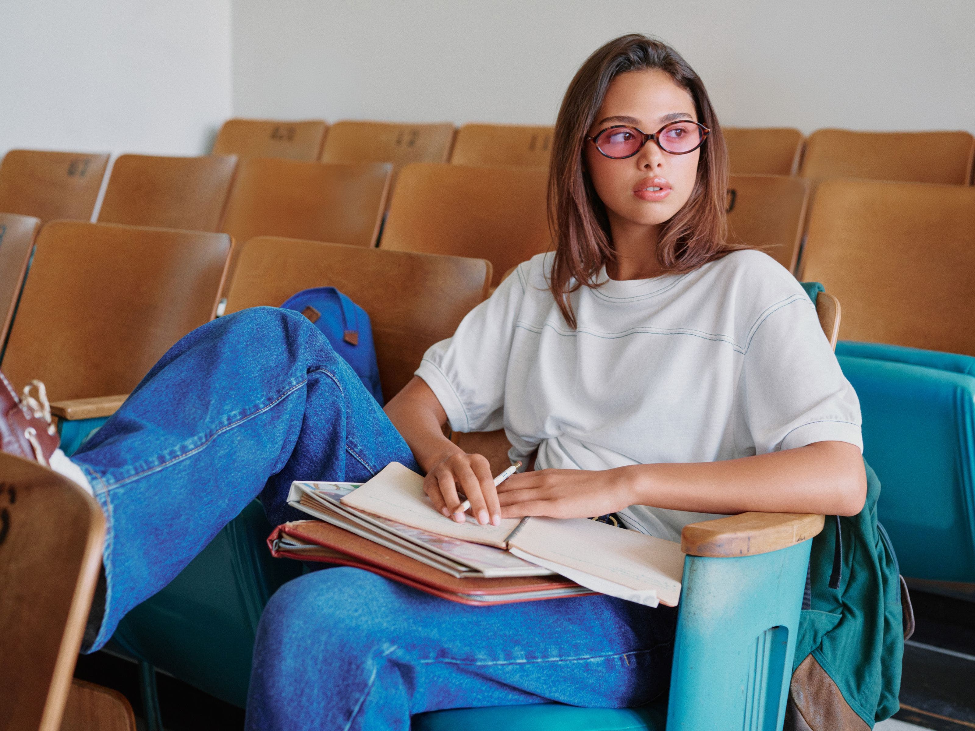 A student in a classroom wearing a Good American tee and jeans. 