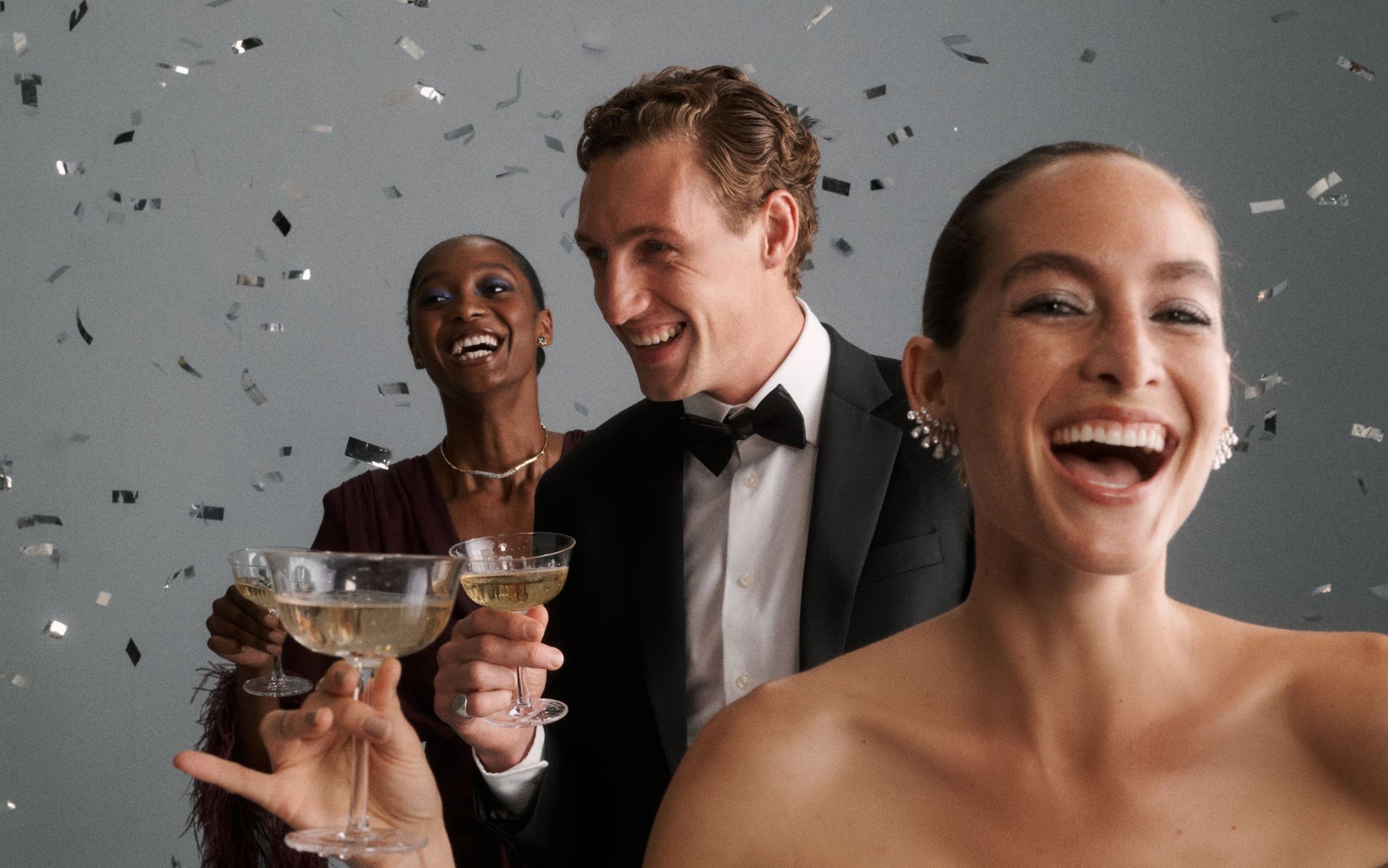 Party guests celebrating with a glass of champagne among confetti.