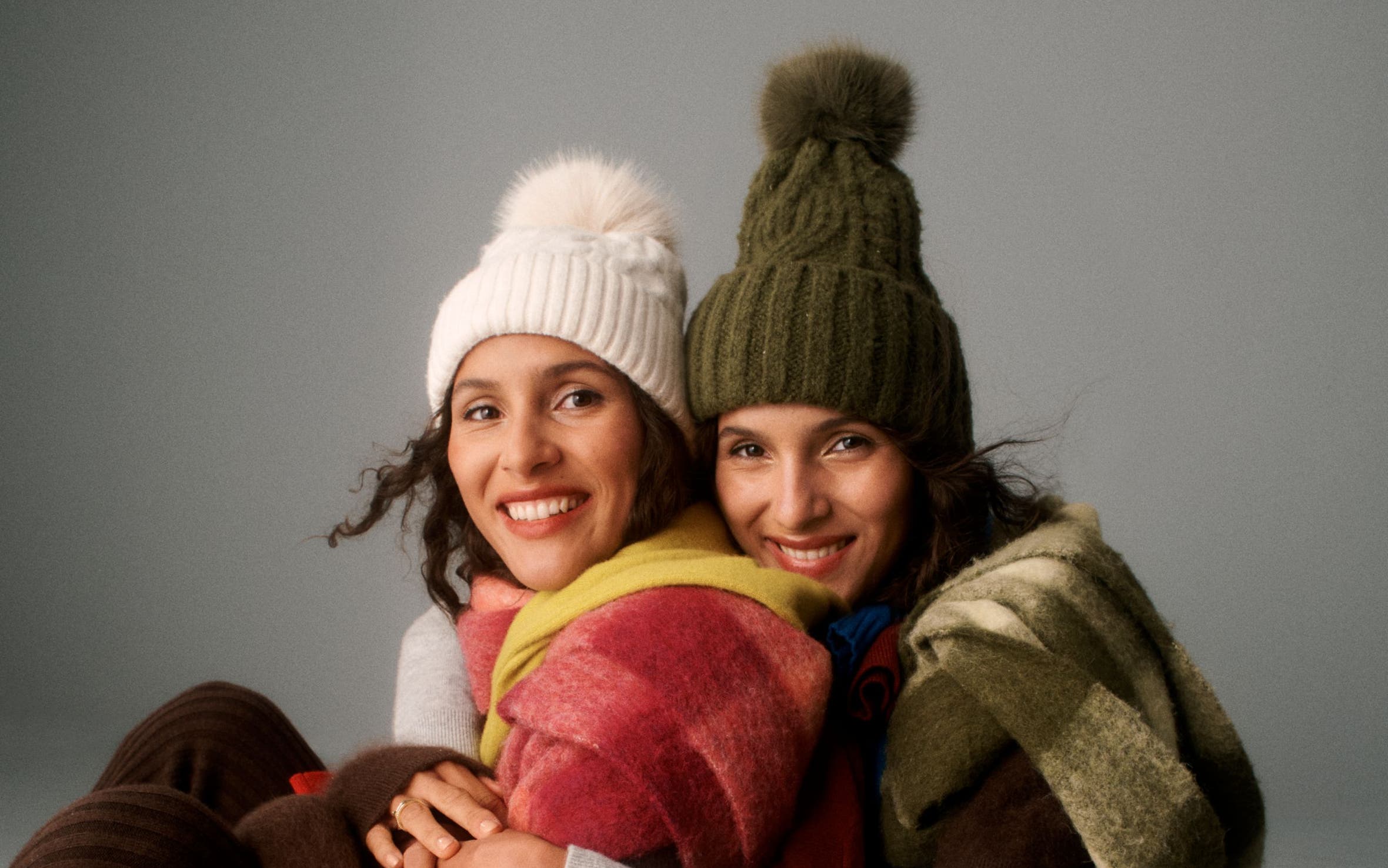 Two women wearing winter accessories.