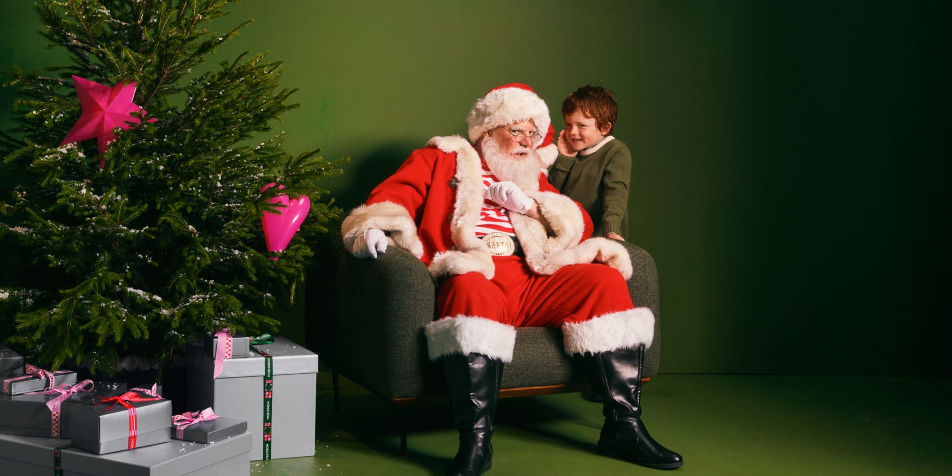 A boy whispering into Santa's ear.