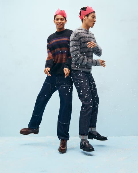 Two men wearing sweaters, jeans and paper crowns. 