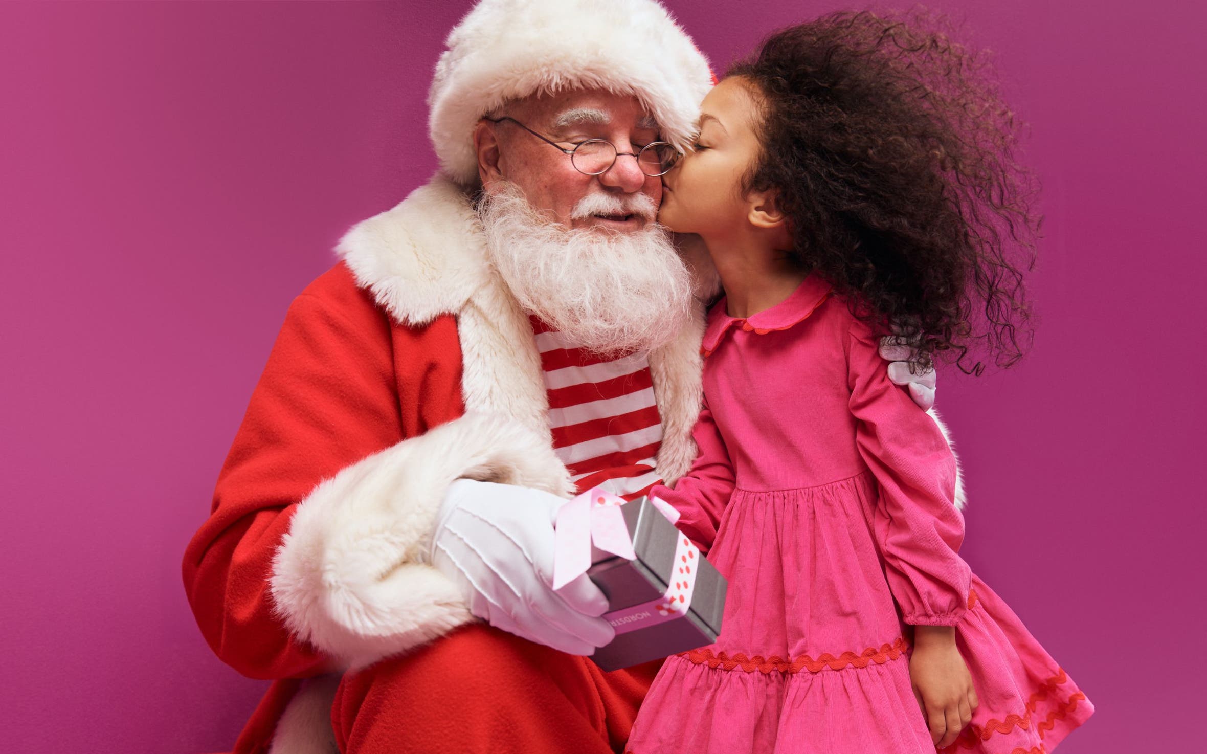 A child kissing Santa on the cheek.