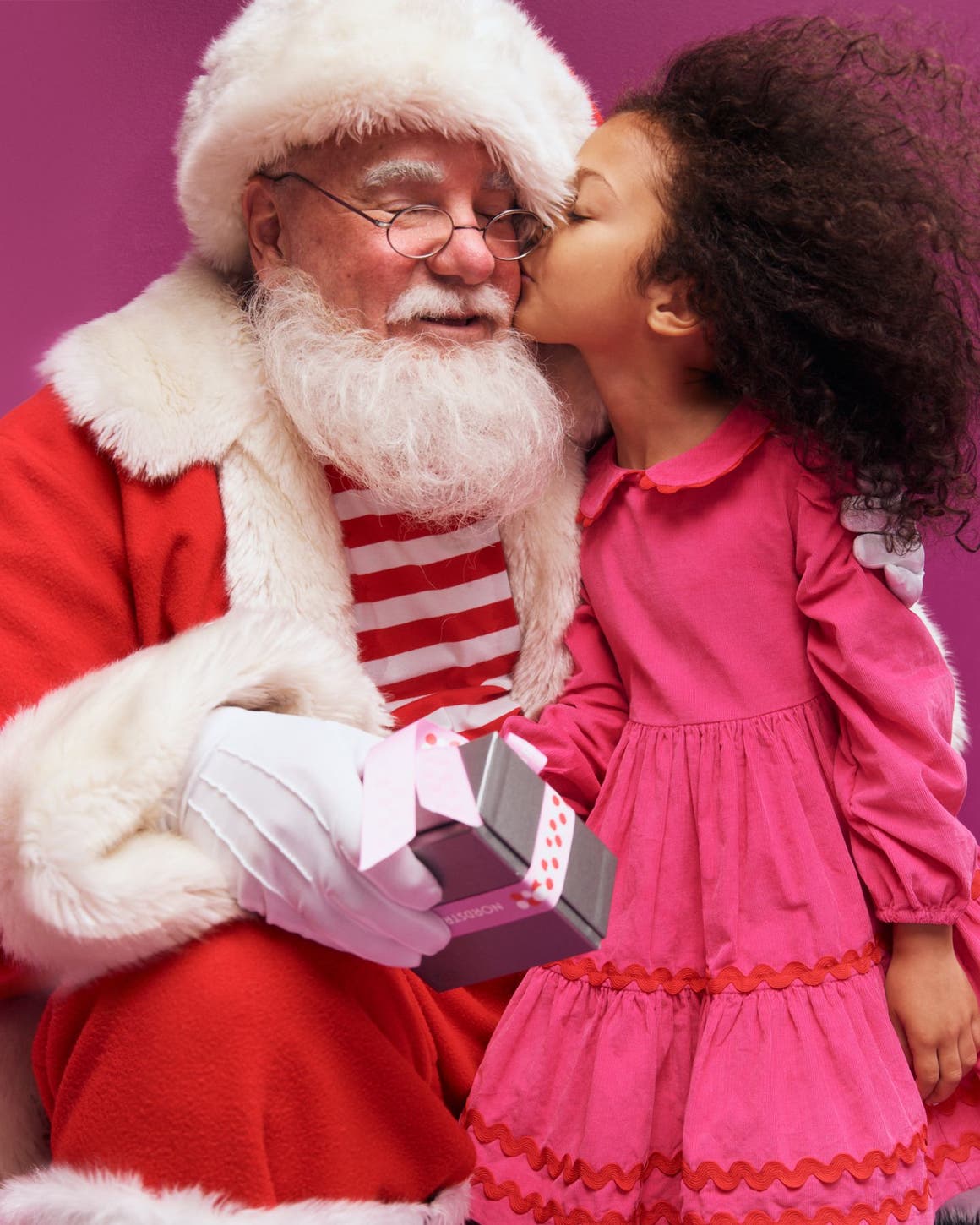 A child kissing Santa on the cheek.