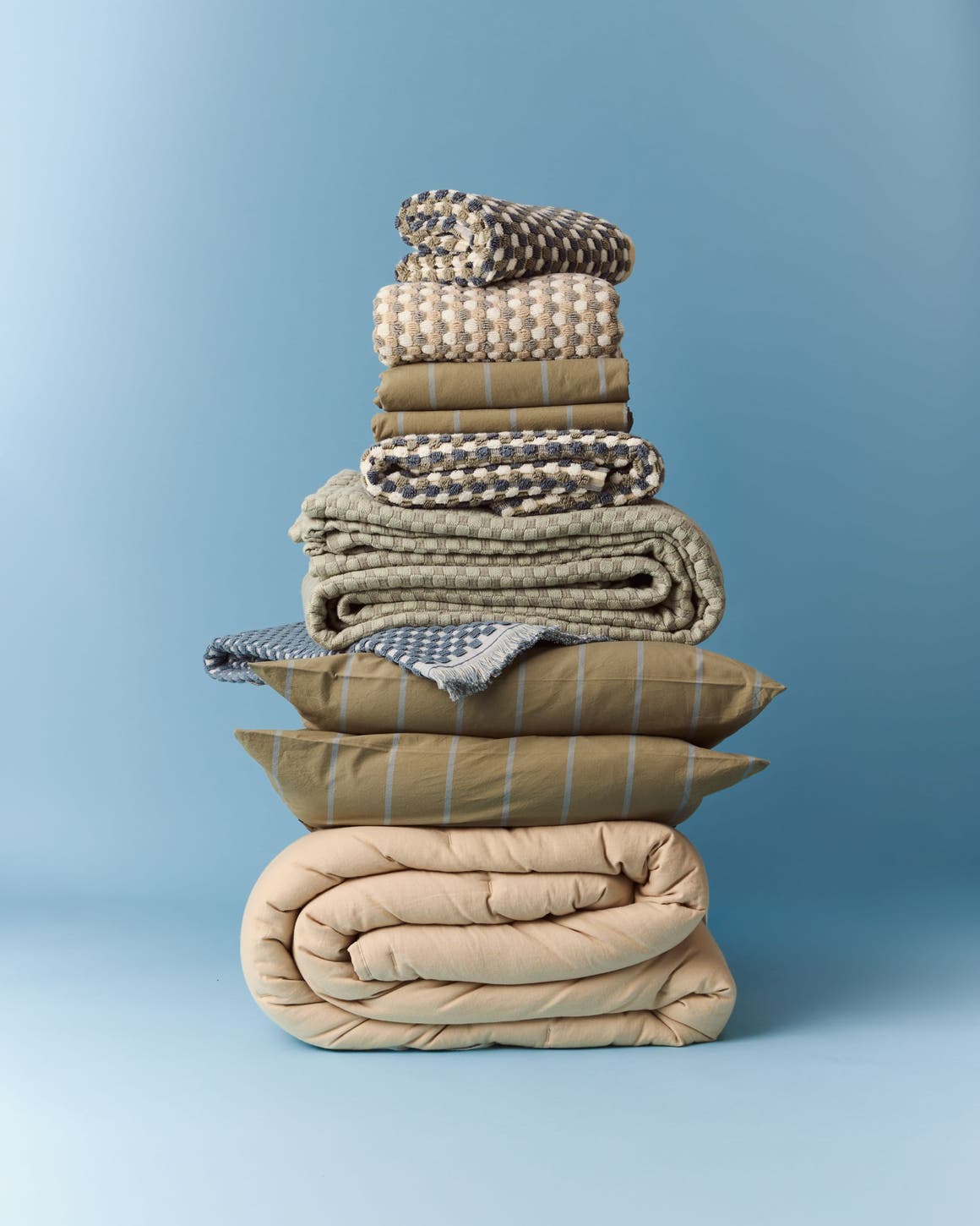 A stack of bed linens in neutral colors.