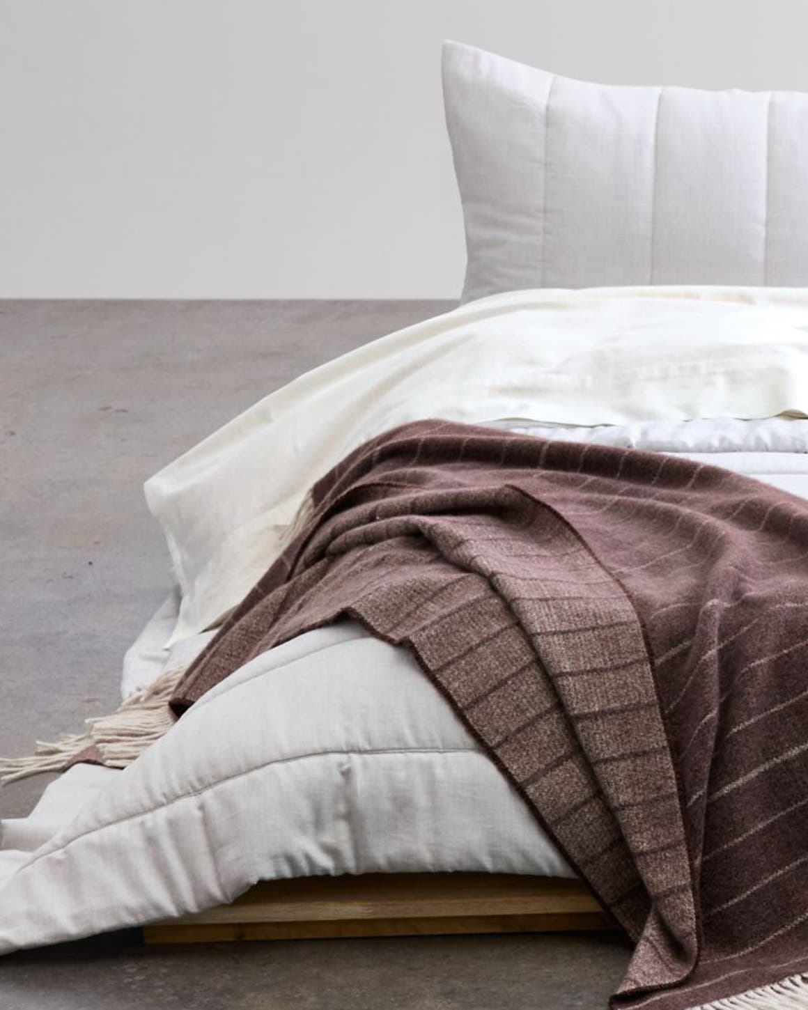 A bed with a comforter and throw blanket.