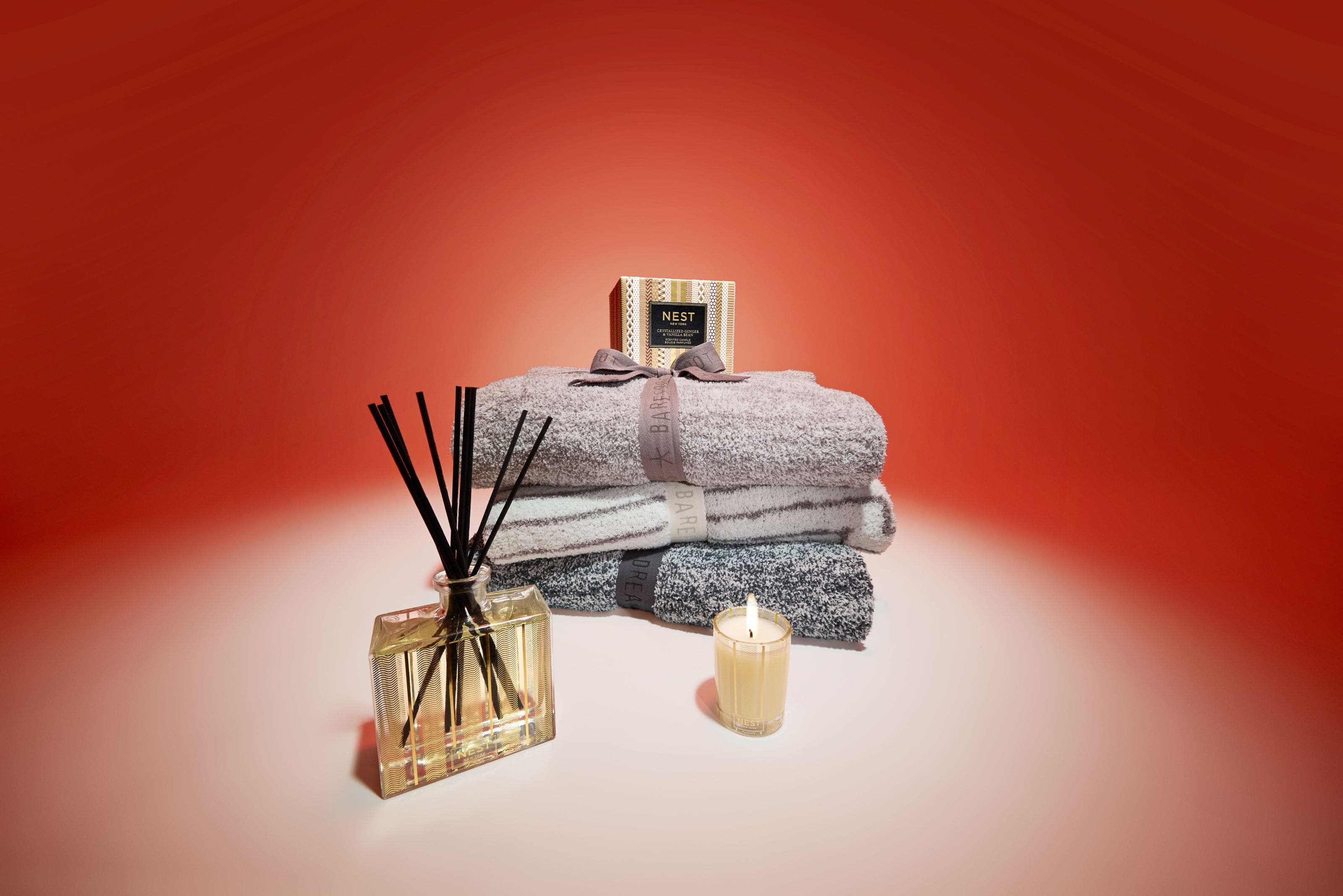 Home fragrance products from NEST New York and a stack of throw blankets. 