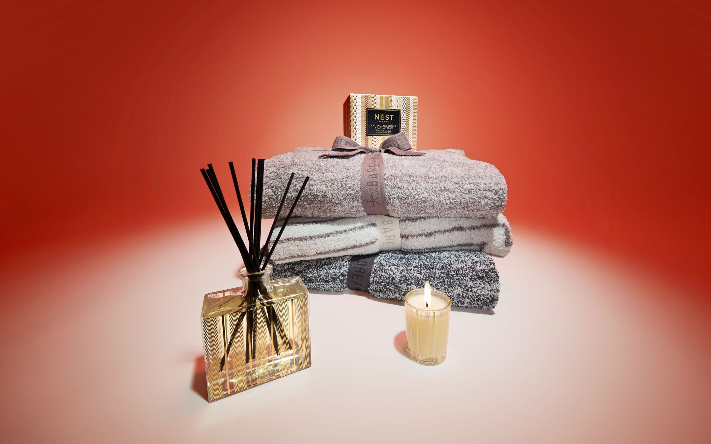 Home fragrance products from NEST New York and a stack of throw blankets.