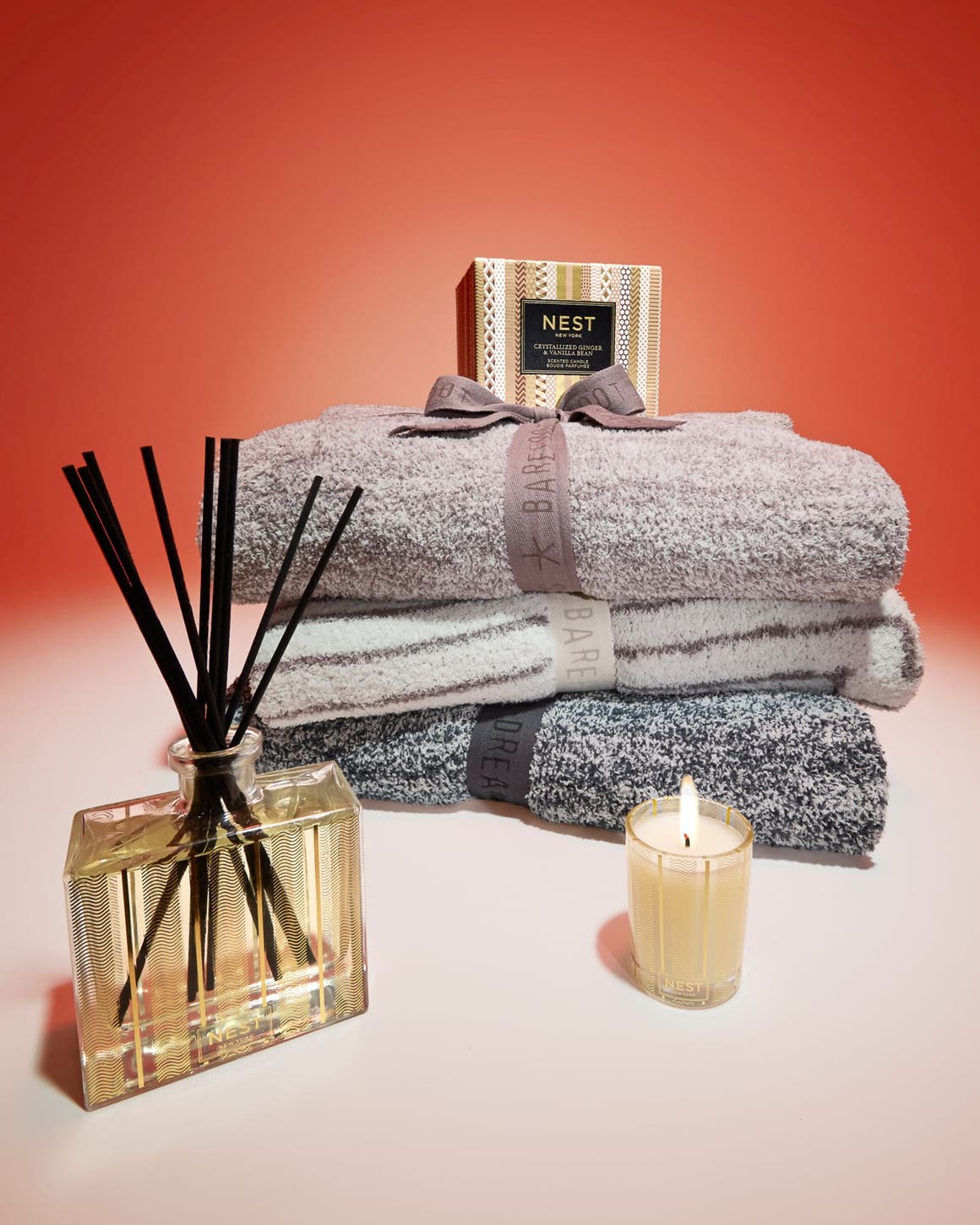 Home fragrance products from NEST New York and a stack of throw blankets.