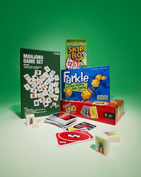 Mahjong set, Skip-Bo, Farkle, and games with loose tiles and cards on green.