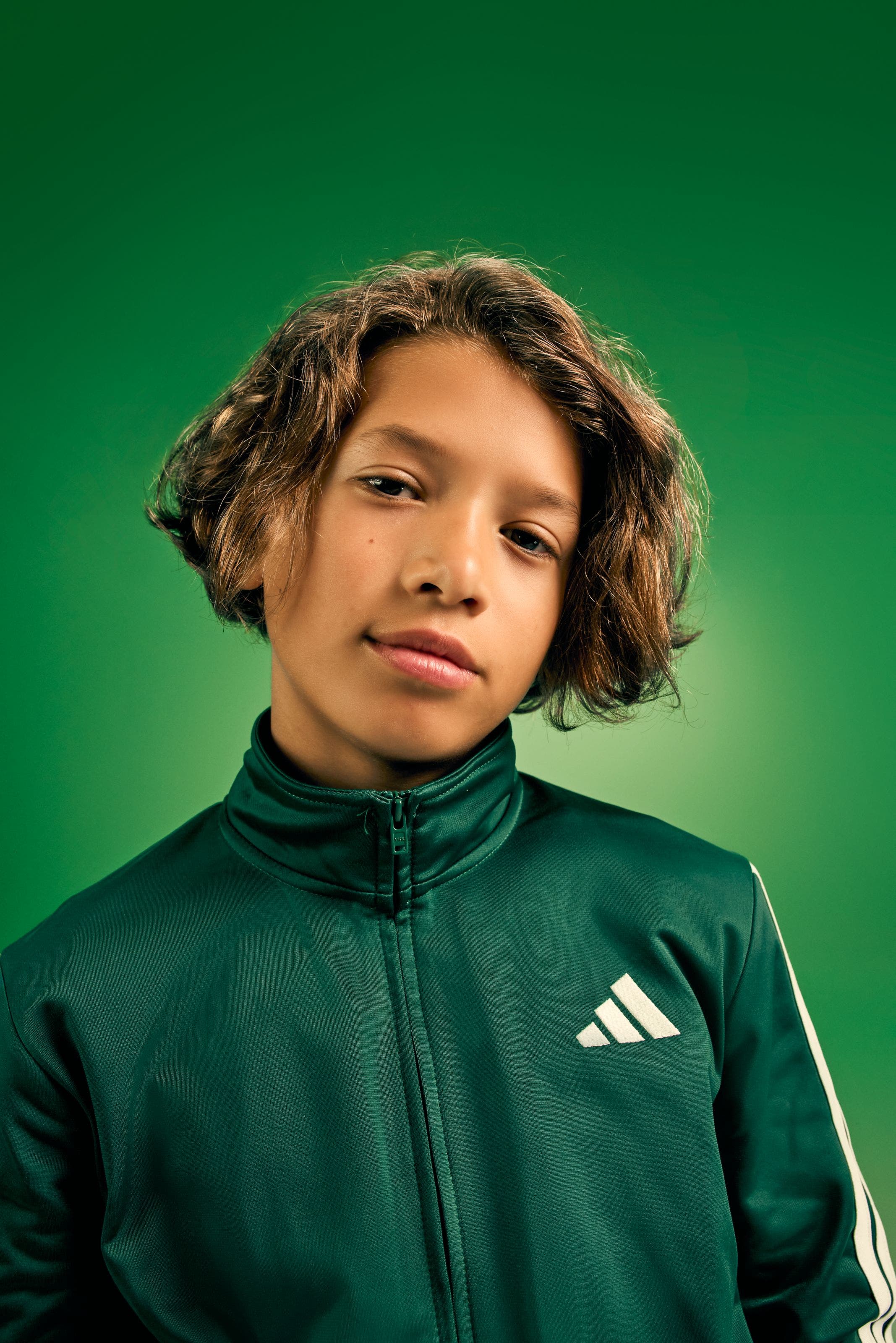 Boy wearing a green adidas zip-up jacket.