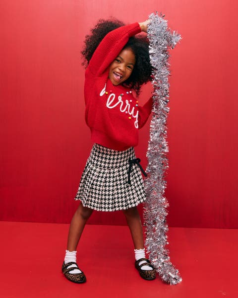 A little girl holding a silver garland.