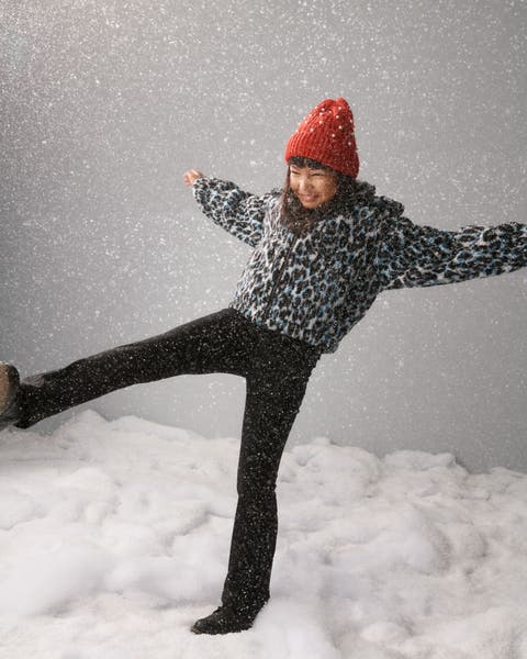 A girl wearing a beanie, animal-print jacket and pants.