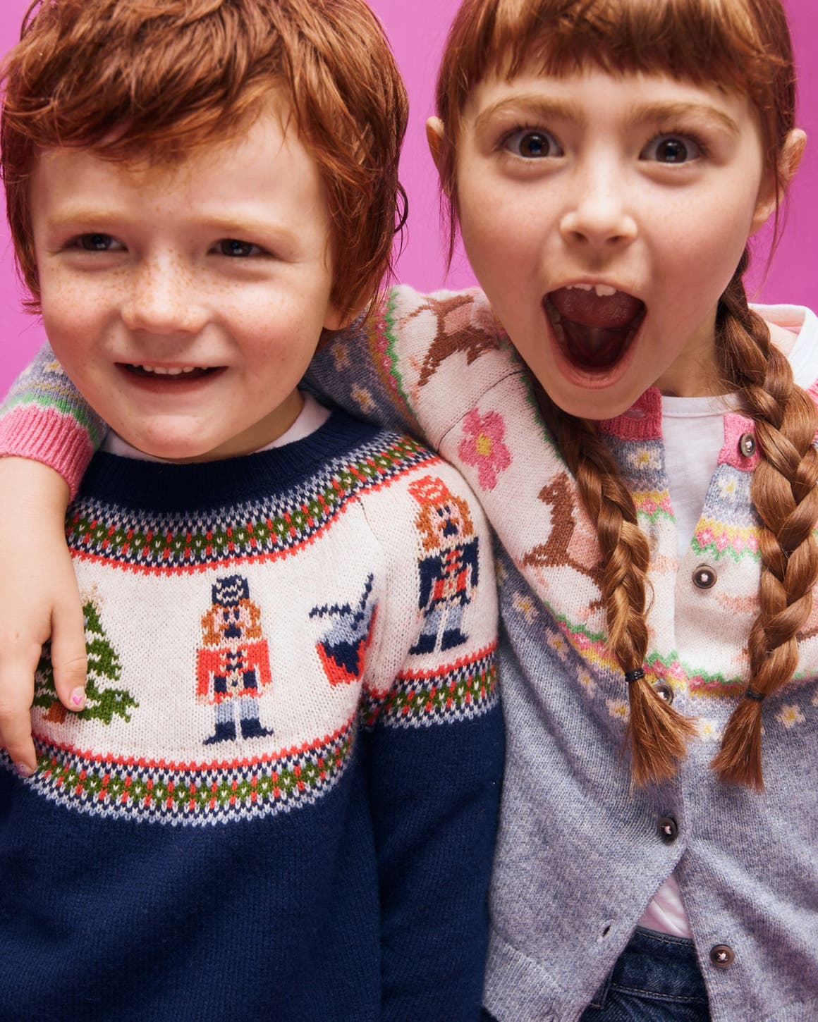 Two smiling children in holiday sweaters.