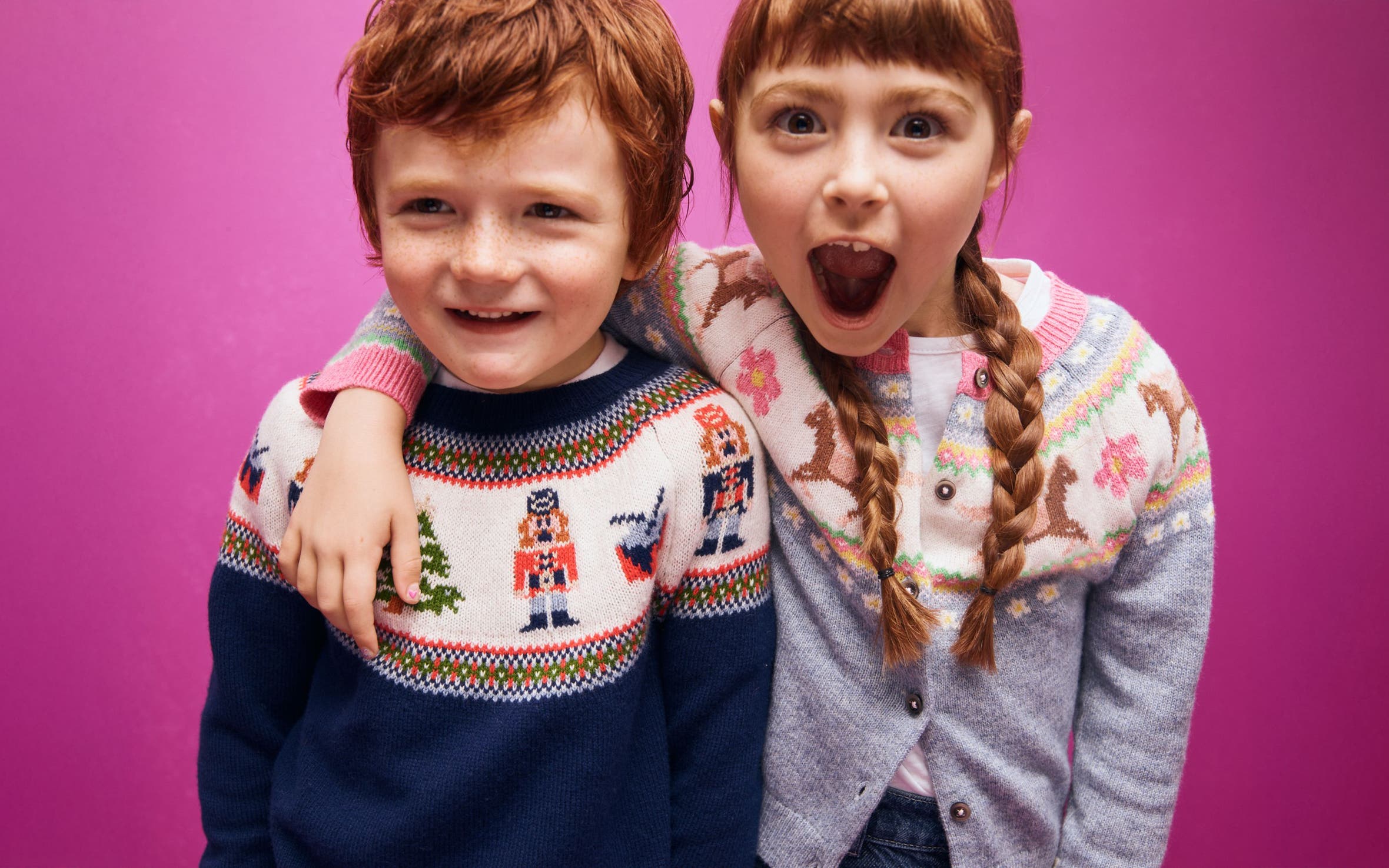 Two smiling children in holiday sweaters.