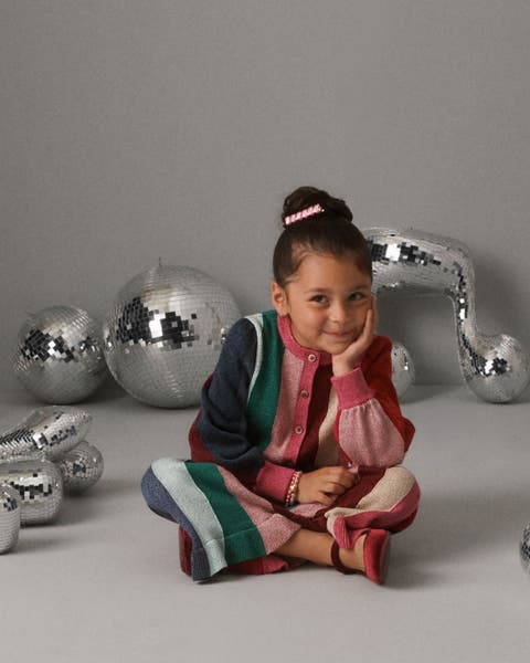 A girl wearing a striped cardigan and matching pants.