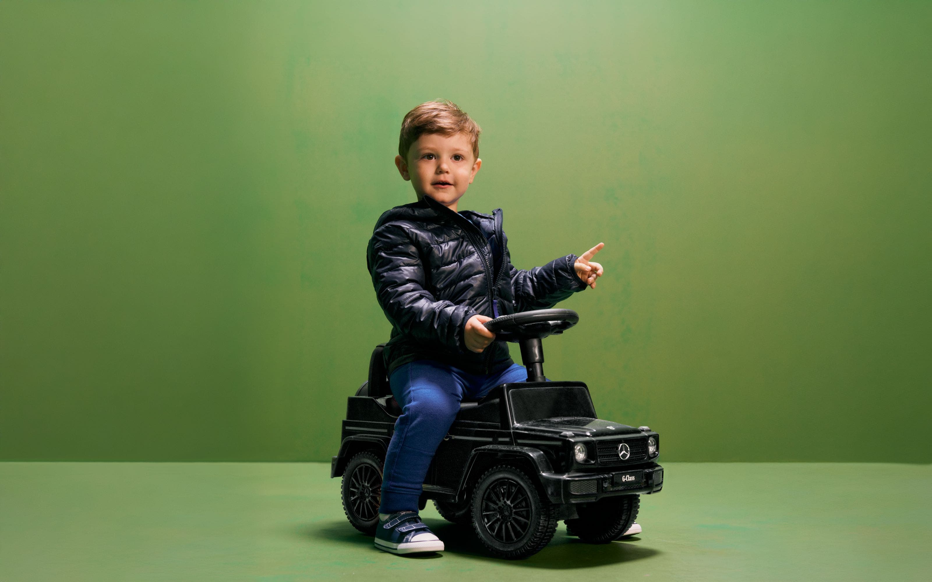 A little boy driving a Mercedes truck.