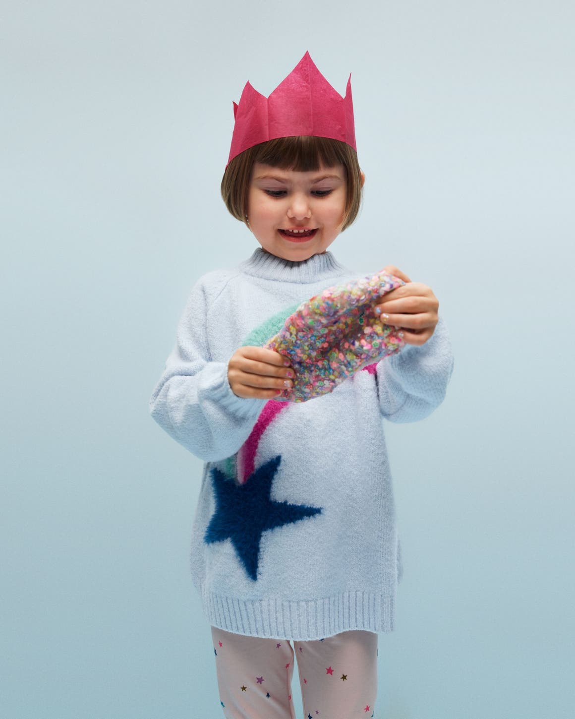 A little girl holding a colorful silicone putty toy.