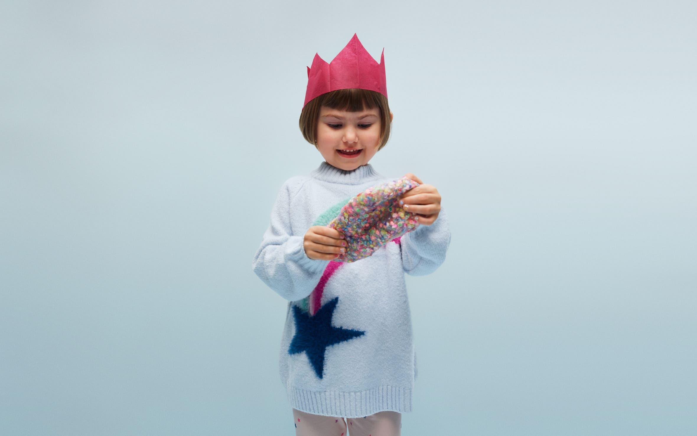 A little girl holding a colorful silicone putty toy.