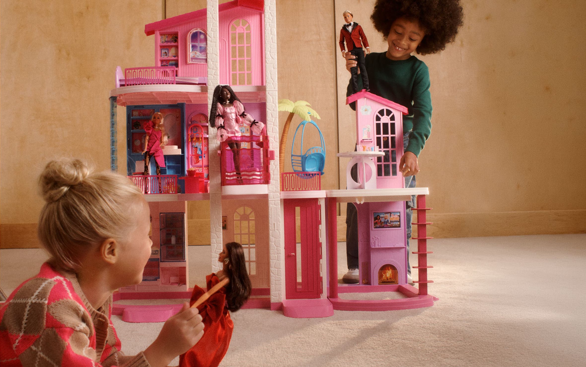 Two girls playing with Barbies in a dollhouse.