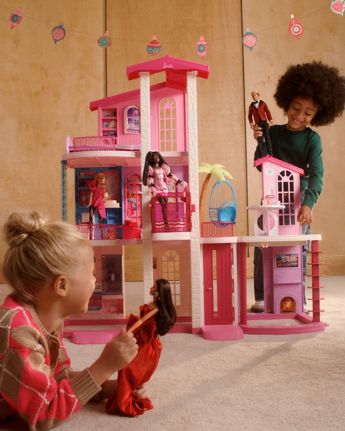 Two girls playing with Barbies in a dollhouse.