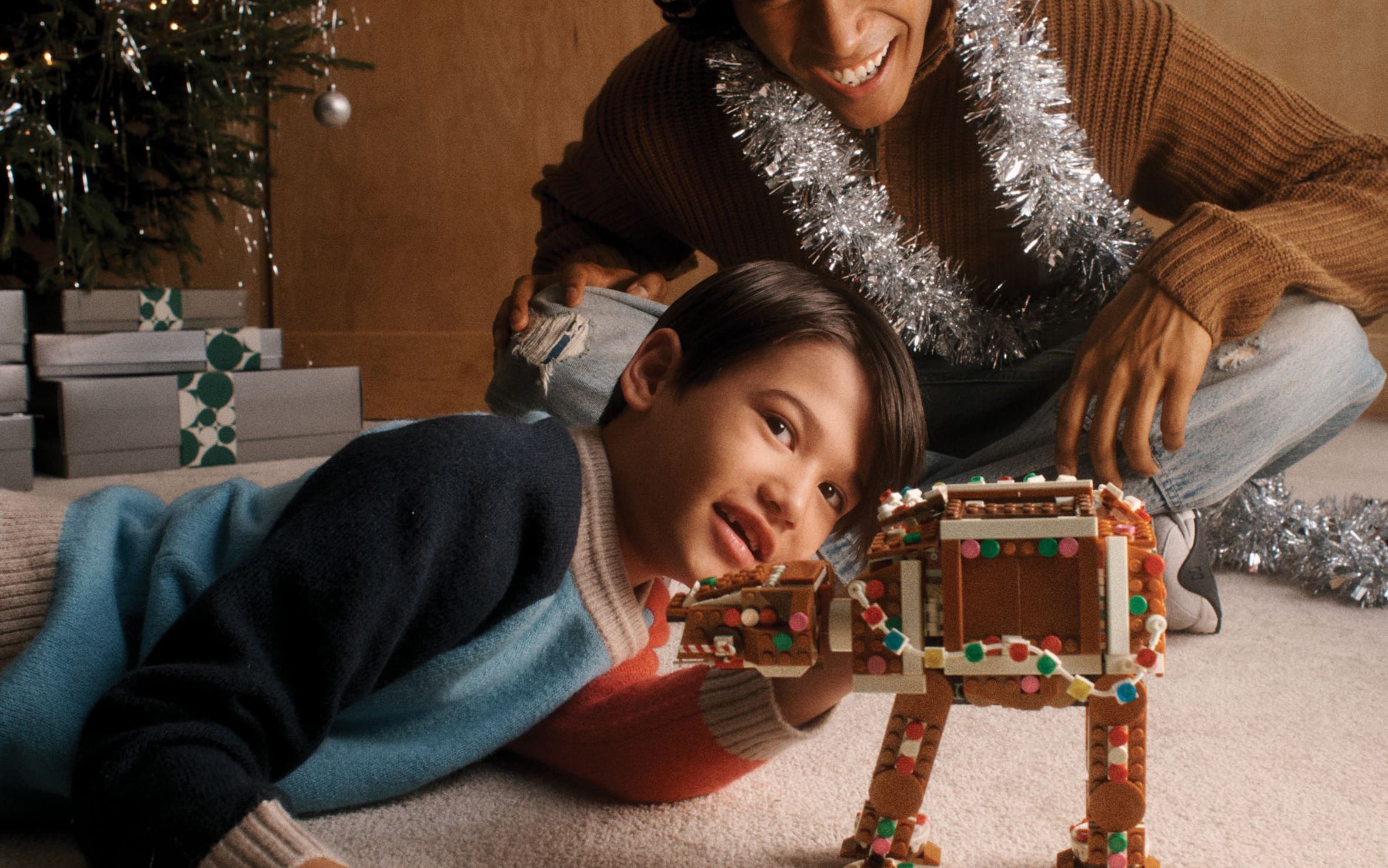 A boy and man playing with a LEGO AT-AT Walker.