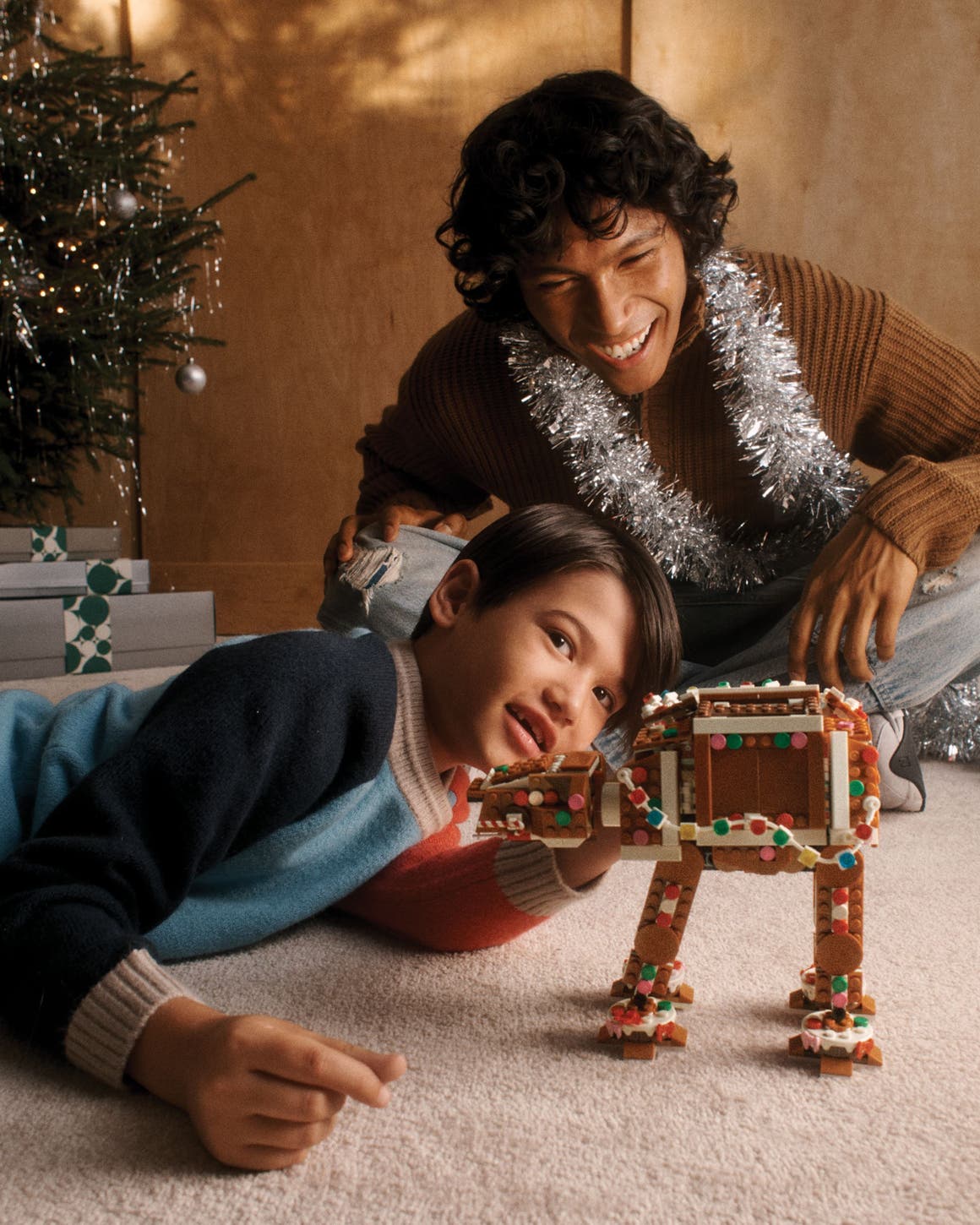 A boy and man playing with a LEGO AT-AT Walker.