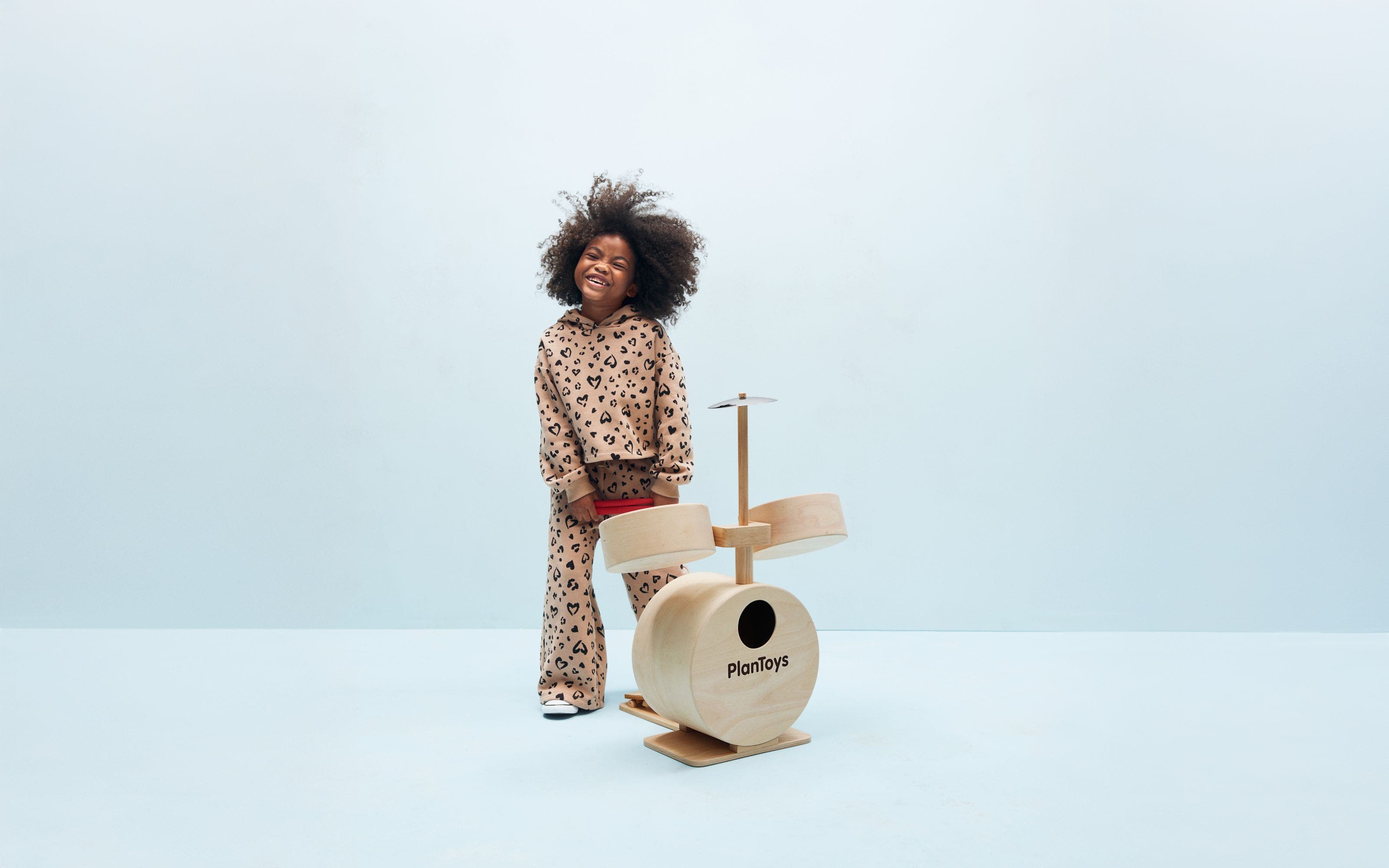 A girl with a toy drum set.