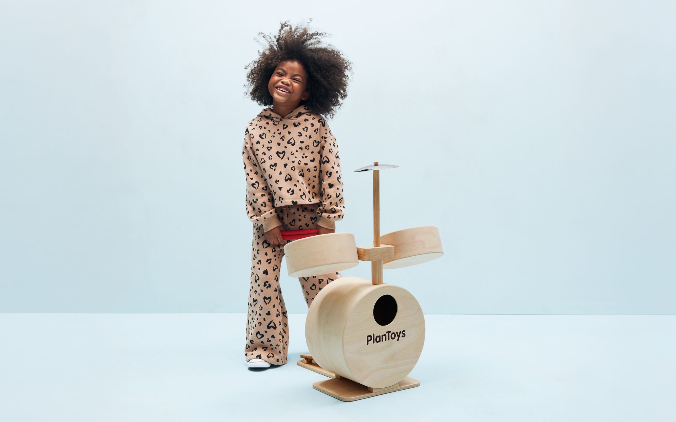 A young girl playing with a wooden drum set.