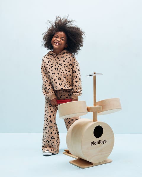 A girl with a toy drum set.
