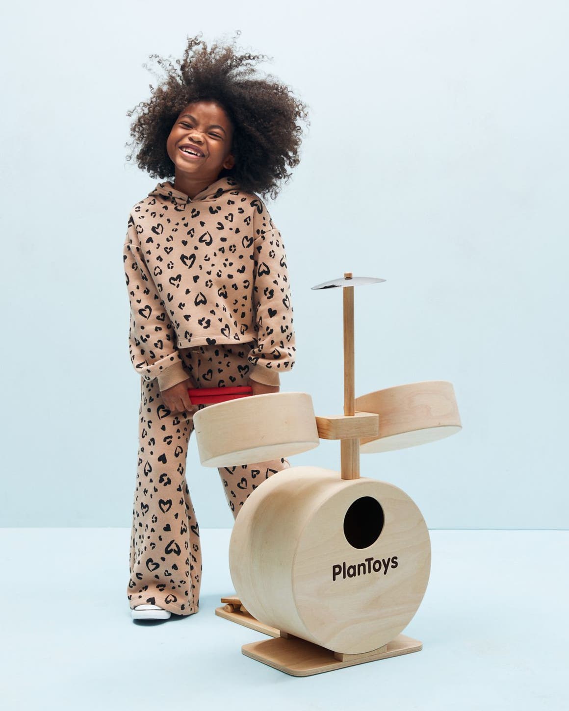 A young girl playing with a wooden drum set.