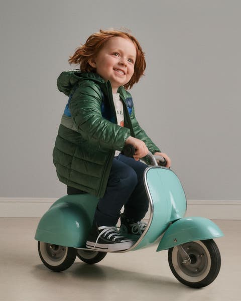 A boy riding a toy scooter.